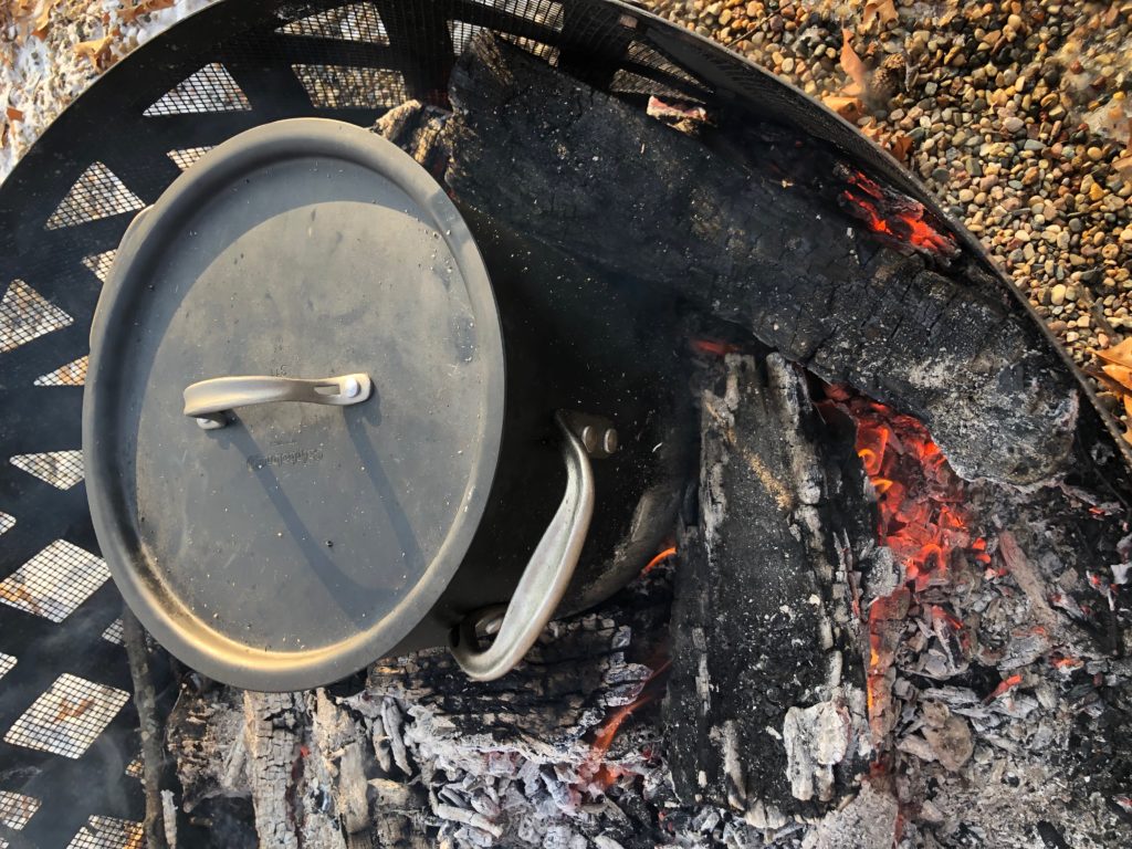 A pot of soup on the coals of a fire
